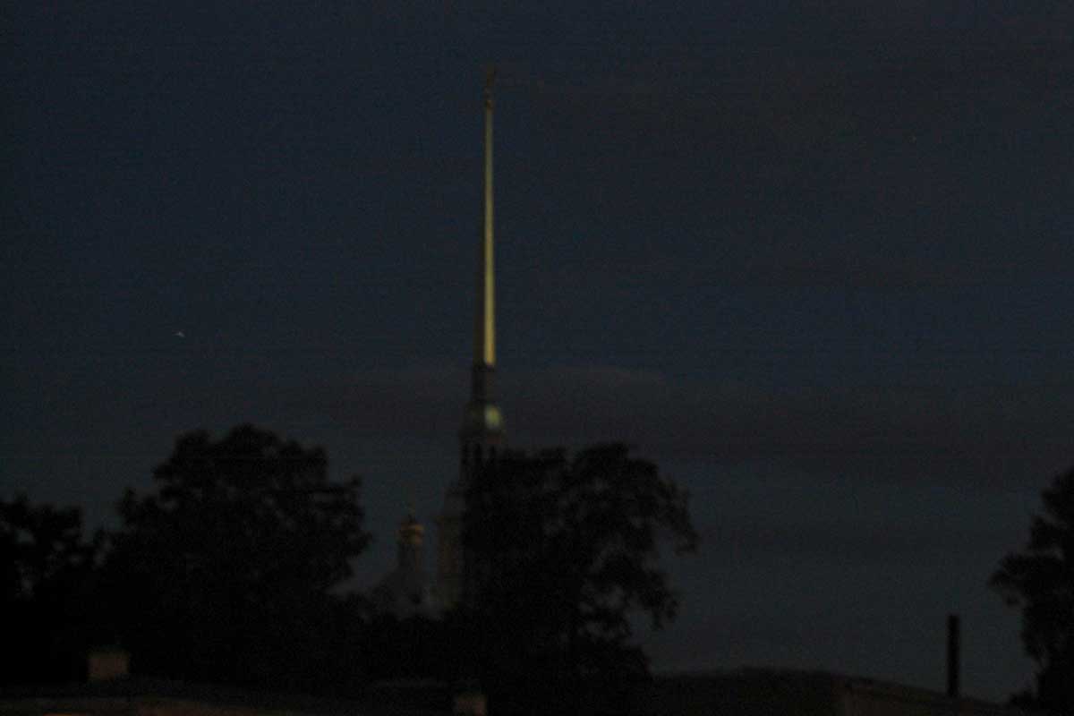 In the summer night the sun that has dipped below the horizon lightens the spire of the Cathedral of Peter and Paul